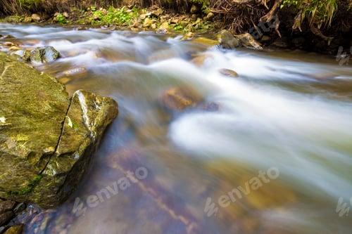 Preview: Fast flowing through wild green forest river with crystal clear smooth silky water falling from big