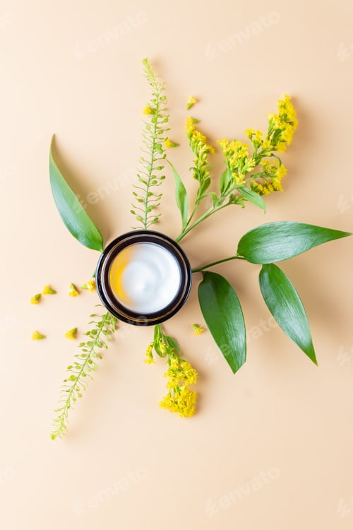 Preview: Dark glass Jar with face cream and spring flower on a beige background. Unbranded cosmetics packagin