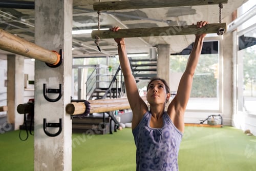 Preview: sportswoman strength training doing pullups at gym