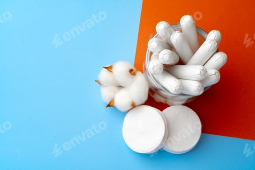 Preview: Female medical tampons and cotton flower on blue paper background