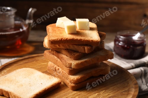 Preview: Slices of tasty toasted bread with butter on table, closeup
