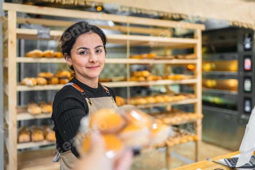 Preview: Baker giving freshly baked buns to customer in bakery shop