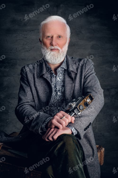 Preview: Old fashioned elderly photographer posing against dark background