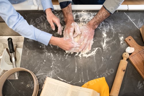 Preview: Hands kneading dough on a flourdusted surface with cooking ingredients and utensils around.