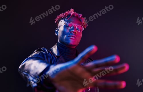 Preview: Having fun. Futuristic neon lighting. Young african american man in the studio