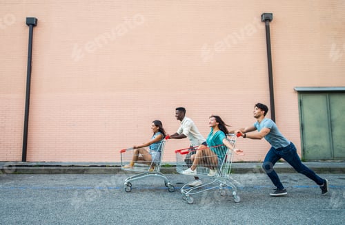 Preview: Young happy friends running with shopping carts