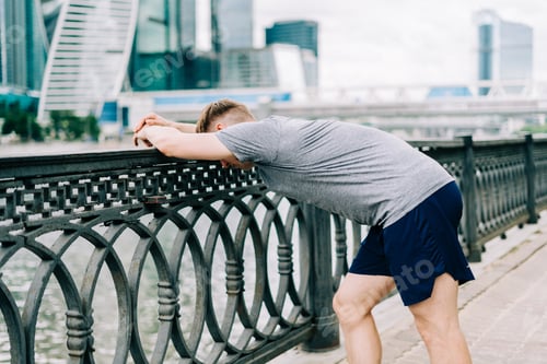 Preview: Athlete relax after workout and morning run at urban city. Sport and healthy concept. Tired man