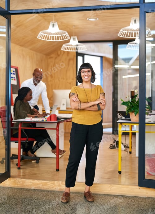 Preview: Shot of a creative businesswoman standing in her office with colleagues blurred in the background