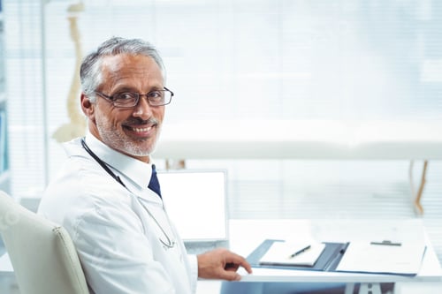 Preview: stethoscope is resting on open laptop beside clipboard on white desk near spine model, copy space