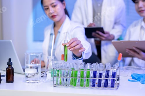 Preview: Close up of asian scientist researcher holding test tube aside laptop and equipment at table in lab.
