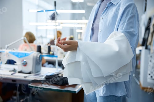 Preview: Cobbler carefully reviews cuff pleats near industrial sewing equipment in bright