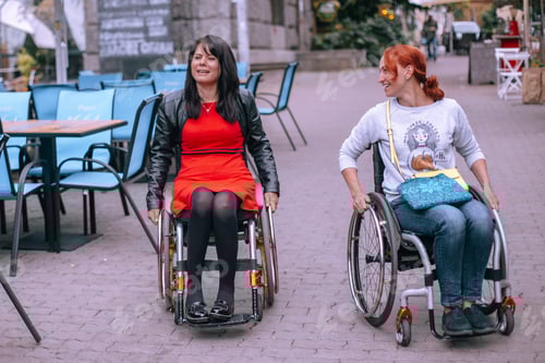 Preview: Girls in wheelchairs laugh on a walk around the city near a street cafe