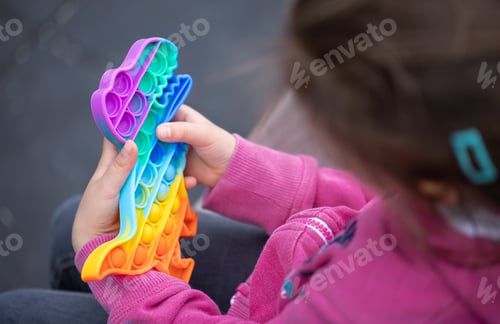 Preview: Close-up of a trendy toy pop it in the hands of a little girl.