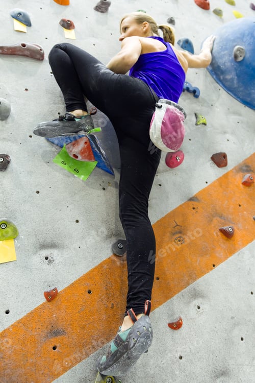 Preview: Fit woman rock climbing indoors at the gym.