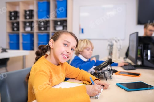 Preview: Pupils sitting at the desk, girl taking notes, boy typing