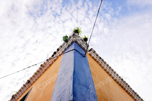 Preview: A lone power cable crosses a street and reaches a corner of a colorful colonial