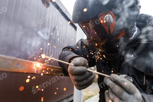 Preview: Welder man welding metal iron with electrodes, worker wearing protective helmet and gloves