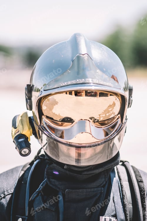 Preview: Firefighter poses with helmet looking at camera.