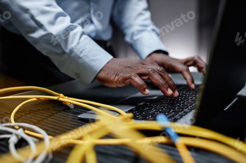Preview: Black man typing at laptop keyboard in server room