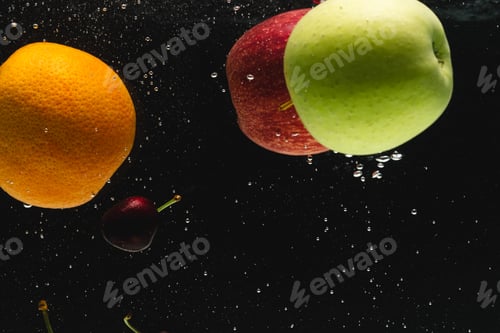 Preview: Close up of fresh fruit falling into water with copy space on black background