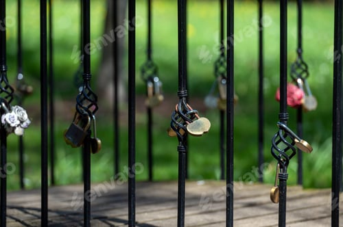 Preview: Love Locks Hanging on Black Iron Fence in Shaded Park on a Sunny Day