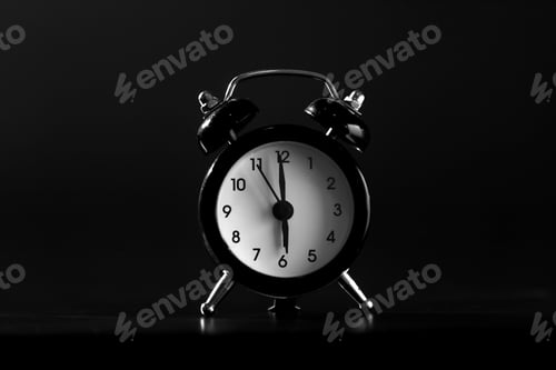 Preview: Black old style alarm clock isolated on black background. close-up