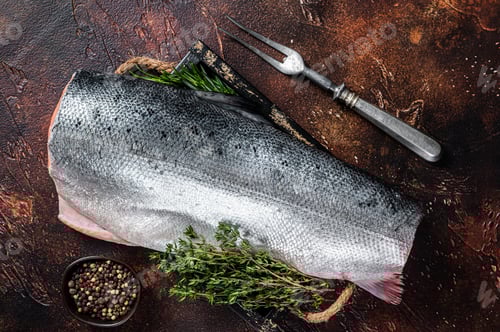 Preview: Slice of Raw cut salmon fish in a wooden tray with thyme. Dark background. Top view