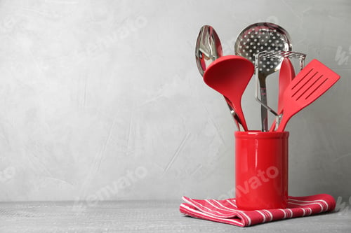 Preview: Holder with kitchen utensils on wooden table against light grey background. Space for text