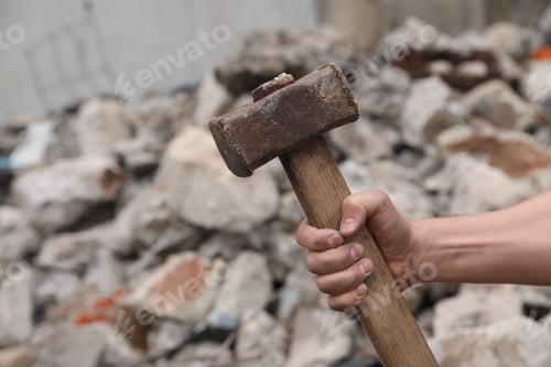 Preview: Man with sledgehammer near pile of stones outdoors, closeup. Space for text