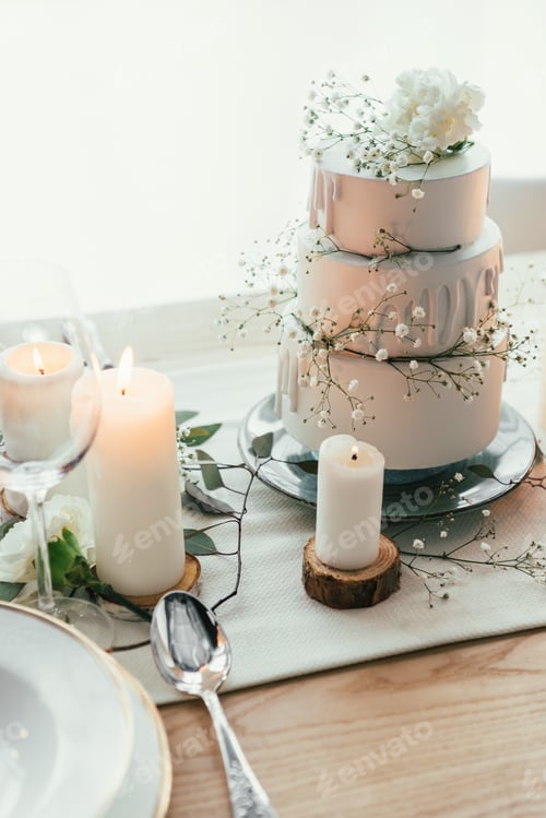 Preview: close up view of stylish table setting with candles and wedding cake for rustic wedding