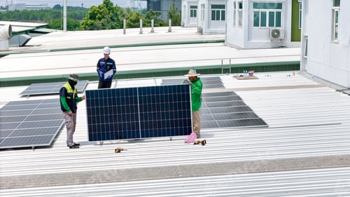 Preview: Aerial view of a rooftop with solar panels, showing a technician in safety performing maintenance.