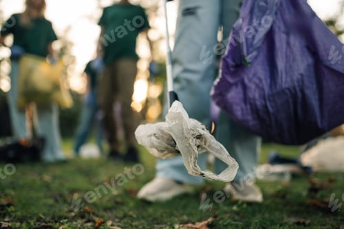 Preview: Volunteer picking up plastic bag during cleanup in park