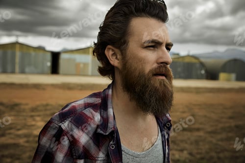 Preview: Serious man with full beard in abandoned landscape