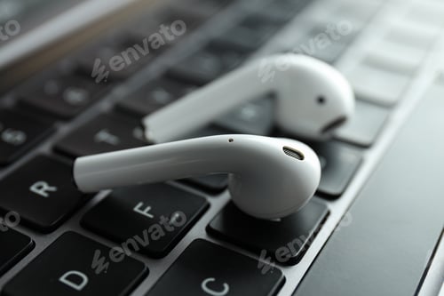 Preview: White, headphones, in-ears on the laptop keyboard.