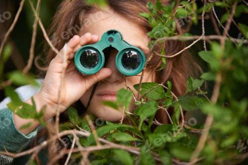 Preview: Bird watching is serious. Shot of a cute little girl looking through a pair of binoculars outdoors.