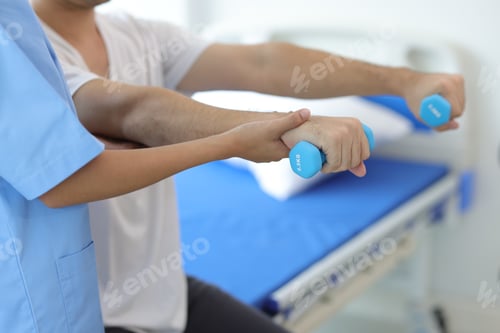 Preview: Nurse in hospital is doing physiotherapy for a male patient's arm with dumbbells.
