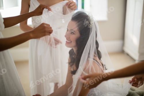 Preview: Bridesmaid assisting bride in wearing veil