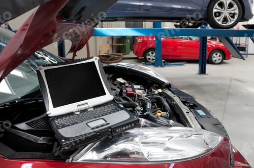 Preview: Car in a workshop and a computer running diagnostics on the engine.