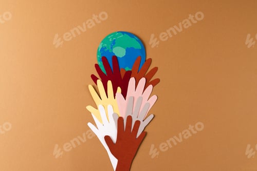 Preview: Paper cut out of multi coloured hands and globe with copy space on brown background