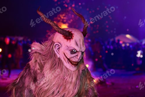 Preview: Krampus dressed in eerie face masks illuminated by a fire in the night