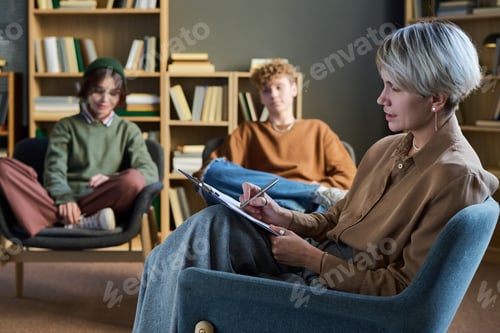 Preview: Adult Woman Taking Notes While Leading Group Therapy Discussion