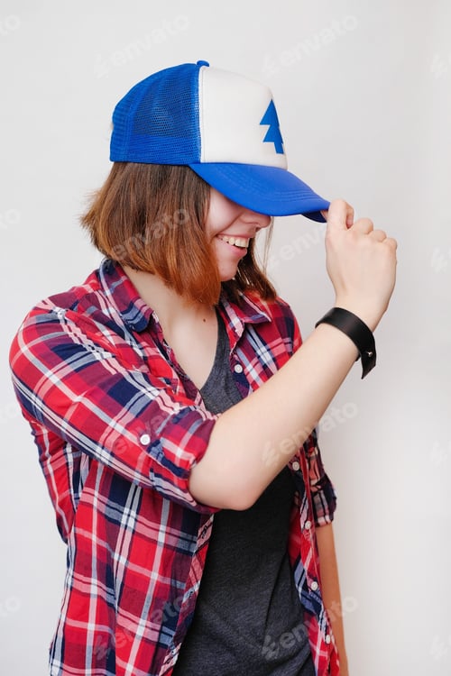 Preview: Hipster In A Plaid Shirt And A Cap. Young Woman On White Background.
