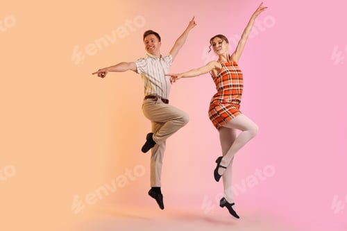 Preview: Happy couple in retro outfits dancing on color background