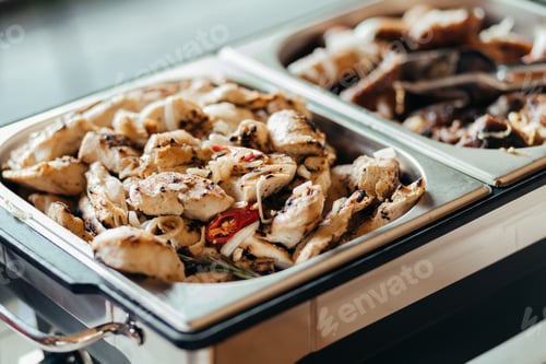 Preview: A close-up view of a chafing dish with two white serving trays filled with poultry