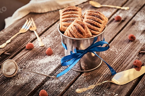 Preview: Puff pastry with jam in a bucket decorated with a blue ribbon on wooden boards with raspberries.
