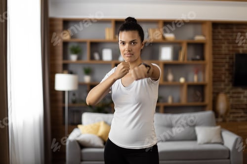 Preview: Strong woman in sport outfit practising in boxing at flat