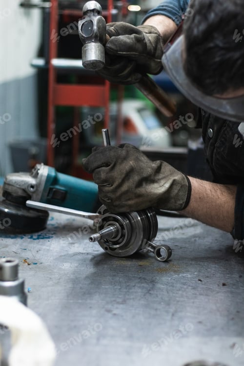 Preview: Anonymous repairman fixing motorbike crankshaft bearing in workshop