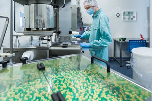 Preview: Pharmaceutical industry man worker in protective clothing operating production of tablets in sterile