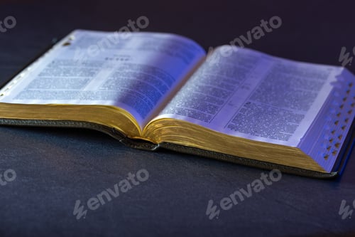 Preview: Open Holy Bible on the table. Religion concept. Bible on black background.