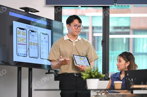 Preview: Man presenting mobile app interface wireframes on digital tablet during a team brainstorming